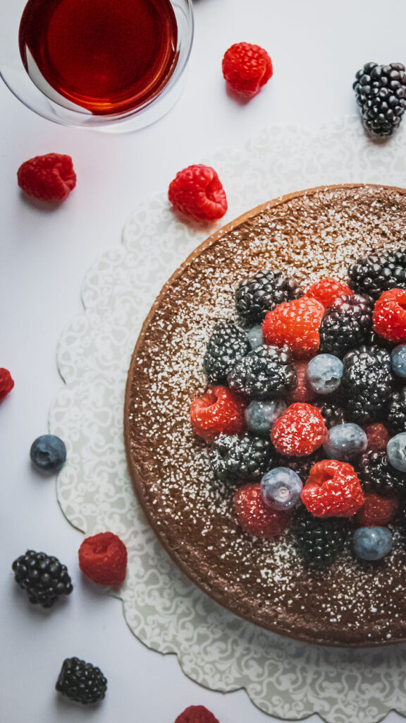 Triple Chocolate Port Wine Cake topped with berries and powdered sugar with a glass of Starboard