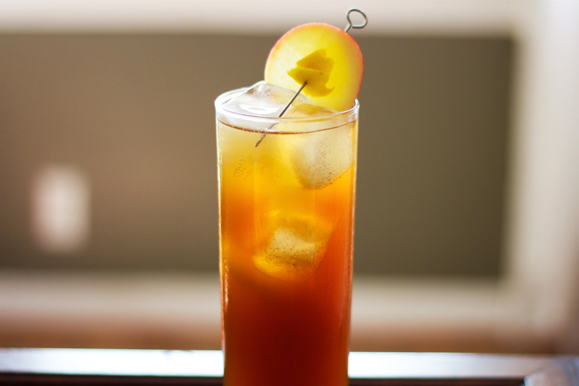 Fall Fizz vermouth cocktail sitting in a high ball glass in front of a window.