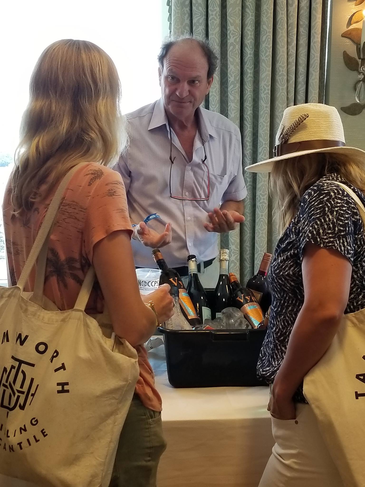 Andrew Quady talking to two young ladies with vermouth and sparkling wine on the table at the vya vermouth tasting and seminar at tales of the cocktail.