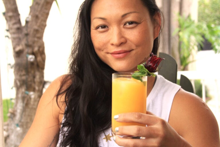 Fitness Trainer Venus Lau sitting outside holding a Vya Vermouth summer cocktail