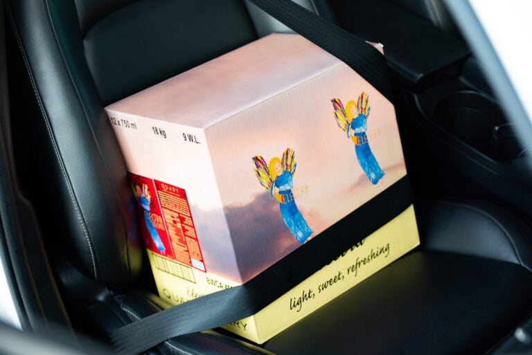 Case of Electra Moscato Wine on the passenger seat of a car with a seatbelt over it.