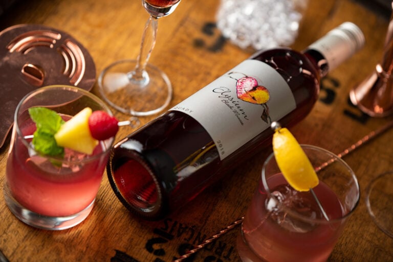 Elysium Black Muscat Dessert Wine lying on a barrel next to cocktails.