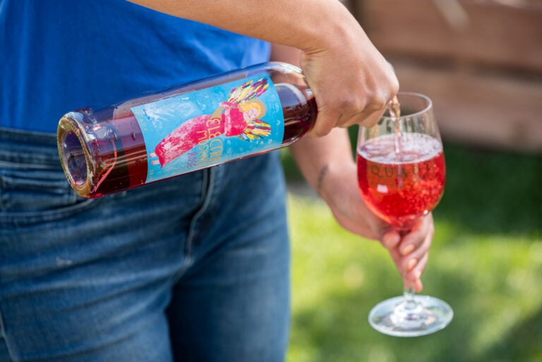 Girl pouring Electra Moscato Rosé into a wine glass outside.