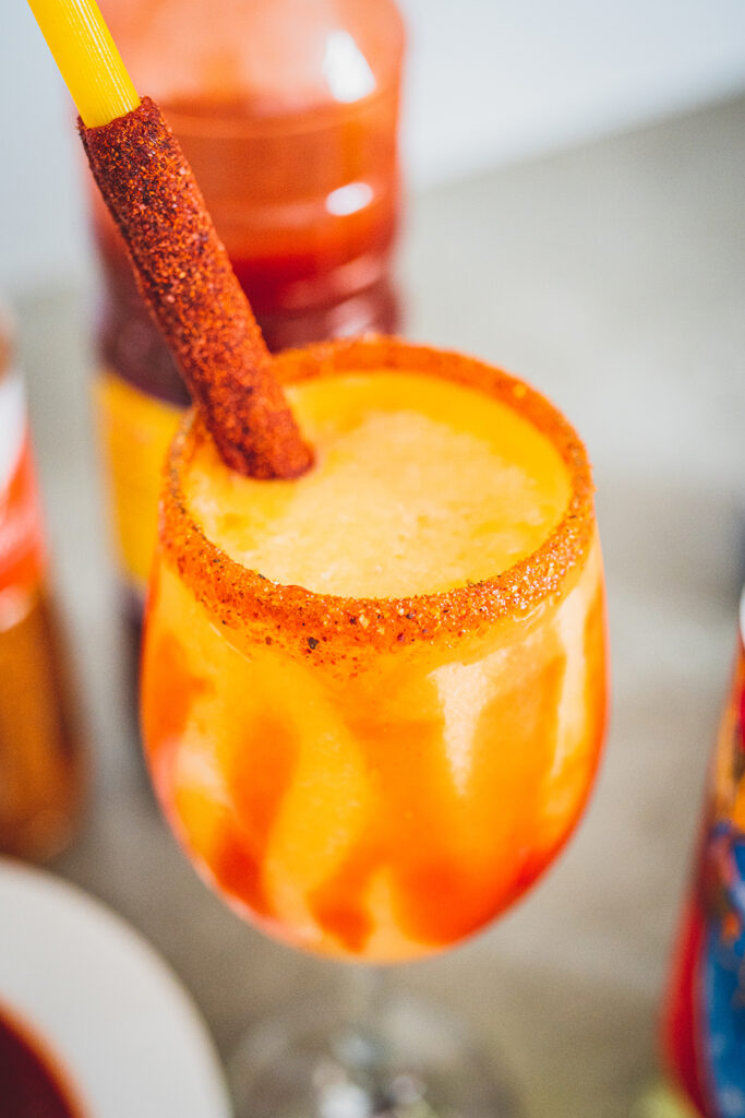 Mangonada rimmed with Tajin and a Chamoy stick