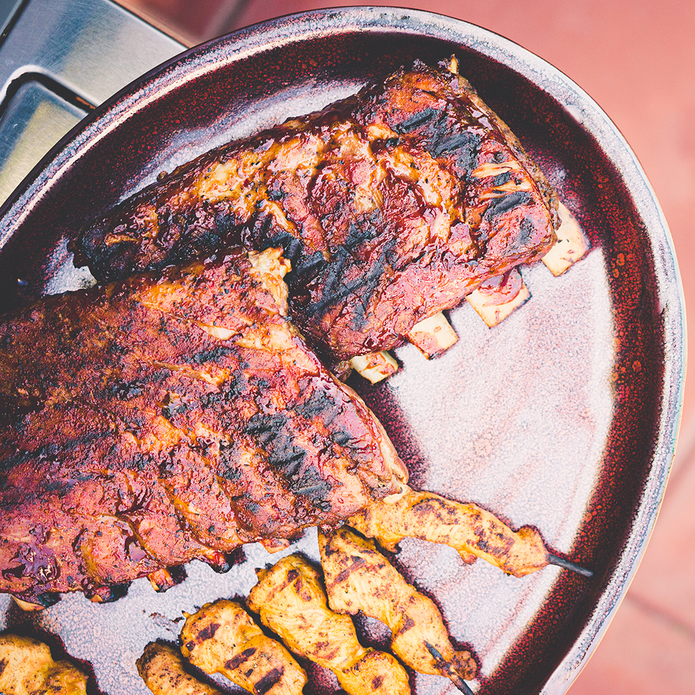 A plate of ribs and chicken skewers hot off the grill