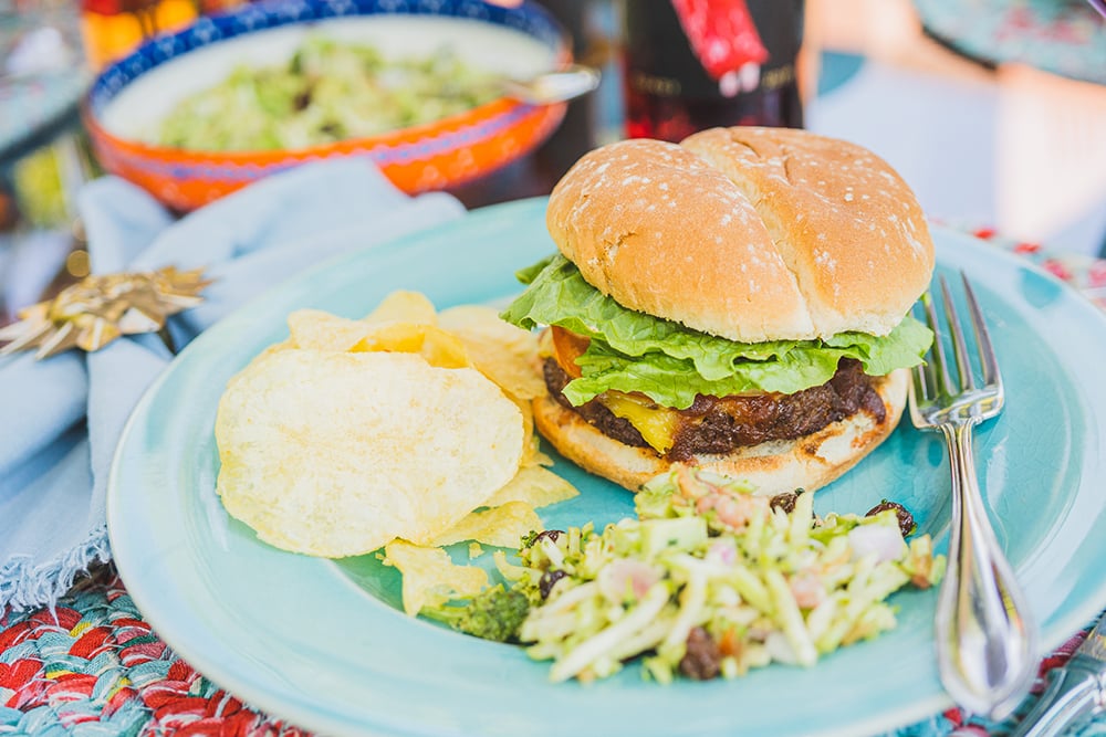 Hamburger, broccoli salad and chips on a plate