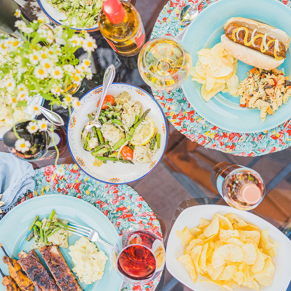 Barbecue side dishes of chips and asparagus salad, with glasses of wine