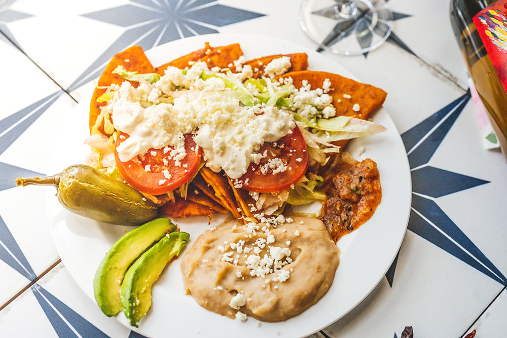 Enchiladas topped with cheese and a side of refried beans